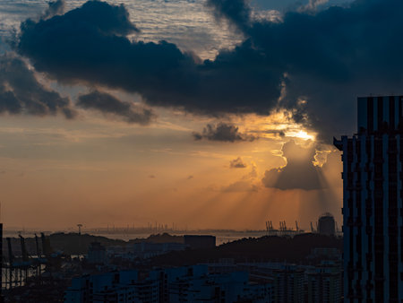 Dark and cloudy sunset in Singapore with the contours of harbour and industrial areas visible along the horizon.の写真素材