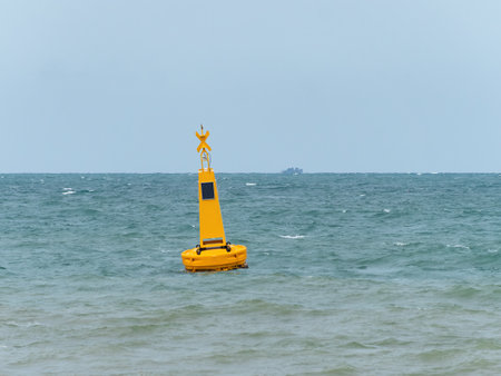 Yellow buoy with a solar powered light at sea to mark a danger area, in this case an area reserved for swimmers near a beach in Pattaya, Thailand.の写真素材