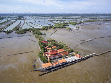Wat Khun Samut Chin in Samut Prakan, Thailand. There was a village around the temple, but when mangrove forests where cleared for shrimp farms, erosion removed the village by 3-5 metres per year. The Bangkok skyline visible in the background.の写真素材