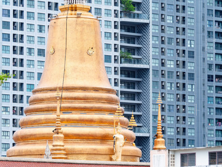Traditional golden pagoda at a Buddhist temple in Thailand in front of a high rise, modern condominium located in Bang Na on the outskirts of Bangkok..の写真素材