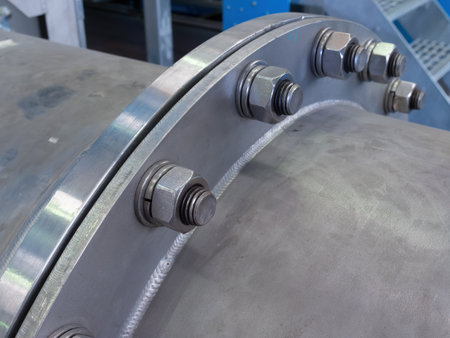 Stainless steel pipe, flange and bolts at an industrial processing plant. Shallow depth of field...