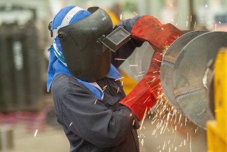 Industrial worker using an angle grinder at the early stages of making a screw conveyor from carbon steel..の写真素材