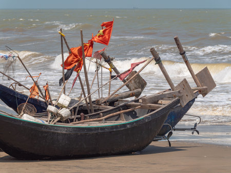 Fishing boats with buoys flying very worn Vietnamese flags at Sam Son Beach, Thanh Hoa, Vietnam. The boats are built from wood, but covered in fiberglass to last longer.の写真素材