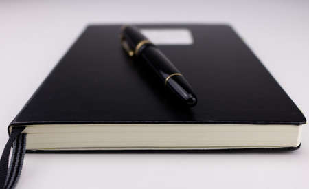 A black fountain pen on top of a closed black notebookの写真素材