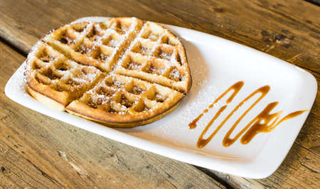 Waffles with caramel sauce on old wooden backgroundの写真素材