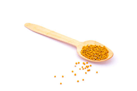 Mustard seeds in wooden spoon isolated on white backgroundの写真素材