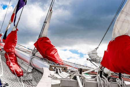 Bowsprit and gathered red sail of the sailing ship.