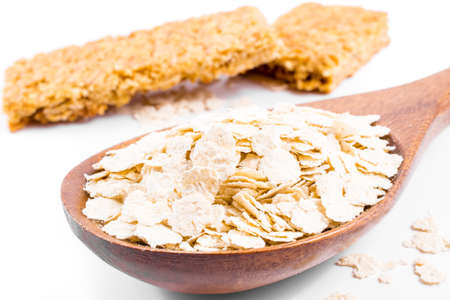 Wooden spoon with oats isolated on white background. Close-up.