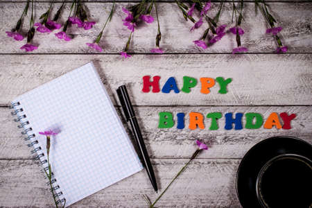 happy birthday concept with top view and copy space.  lilac flowers, notebook and coffee cup on...