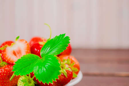 strawberries in bowl on wooden background with copy space and low key.の写真素材
