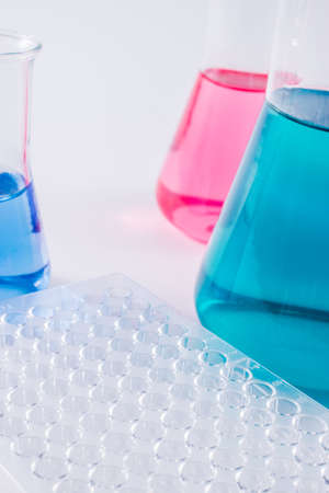research, science and clinic background. 96 well micro plate and  laboratory beakers with colorful...