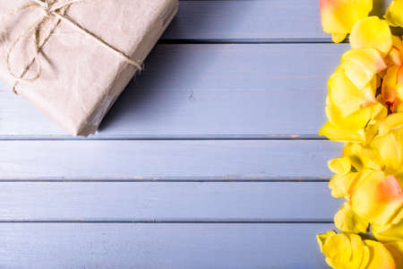 rose flowers leaves close-up and gift box on wooden background. Spring summer border template. mock-up floral background. sale, greeting and celebration card concept.の写真素材