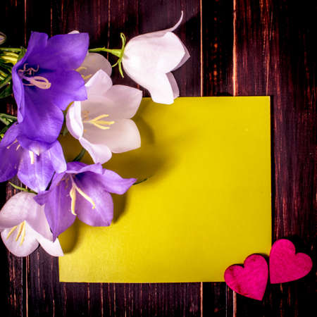 green mockup card with copy space and pink hearts and spring flowers on wooden background. sale, greeting and celebration card concept.の写真素材