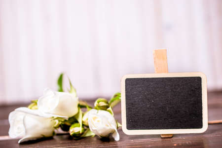 blank sale chalkboard with copyspace and white rose flowers on wooden background. sale and greeting card concept.の写真素材