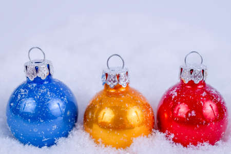 Close-up of colorful xmas balls under snowflakes in snow. Christmas and New Year concept with copy space. Christmas greeting card.の写真素材
