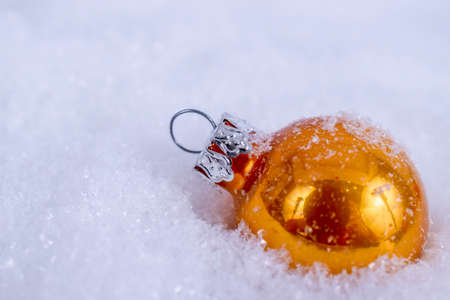 Close-up of yellow xmas ball under snowflakes in snow. Christmas and New Year concept with copy space. Christmas greeting card.の写真素材