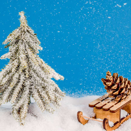 Christmas tree in snow and snowflakes with sledge and xmas cone or strobilus. Christmas and New Year concept. Christmas greeting card.の写真素材