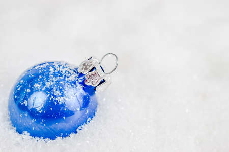 Close-up of blue xmas ball under snowflakes in snow. Christmas and New Year concept with copy space. Christmas greeting card.の写真素材