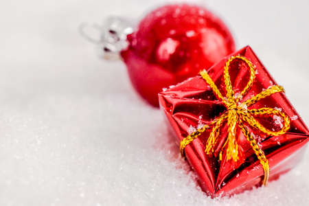 xmas red gift and red Christmas ball under snowflakes in snow with copy space. Christmas and New Year concept. Christmas greeting card.の写真素材