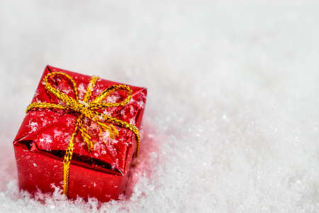 xmas red gift under snowflakes in snow with copy space. Christmas and New Year concept. Christmas greeting card.の写真素材