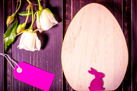 easter egg and rabbit with white rose flowers close-up and sale label or tag on dark wooden background with copy space. easter sale, greeting and celebration card concept.の写真素材
