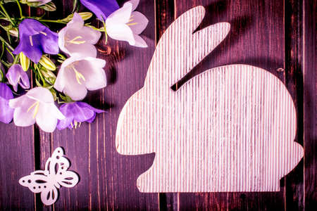 Easter rabbit with spring flowers close-up on dark wooden background. Easter mock up template. Easter sale, greeting and celebration card concept.の写真素材