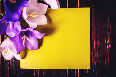 green mockup card with copy space and flowers on wooden background. sale, greeting and celebration card concept.の写真素材