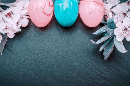 easter eggs and cherry blossom or sakura flowers on stone background with copy space. border template, easter greeting and holiday card.の写真素材