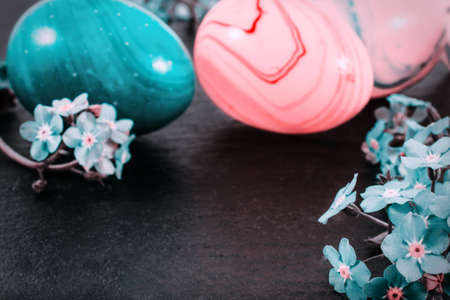 close-up of colorful easter eggs and forget-me-not spring flowers on stone background with copy space. border template, easter greeting and holiday card.の写真素材