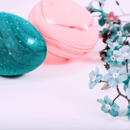 close-up of colorful easter eggs and forget-me-not spring flowers on white background with copy space. border template, easter greeting and holiday card.の写真素材