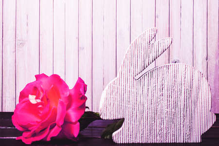 wooden easter rabbit with rose flowers on wooden background. template with copy space. Happy Easter...