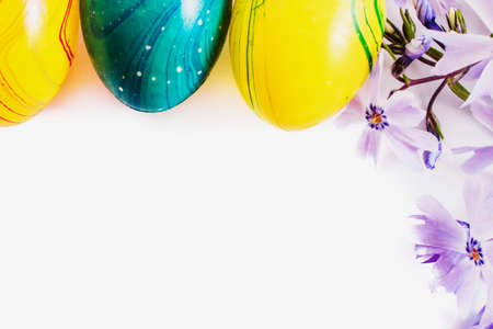 close-up of colorful easter eggs and phlox flowers on white background with copy space. border...