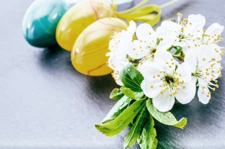 easter eggs and cherry blossom or sakura flowers on stone background with copy space. border...