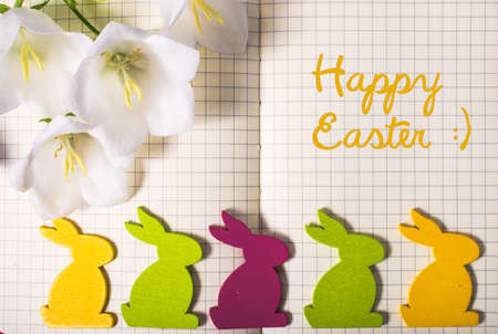 Happy Easter. note book close-up with spring flowers, colorful easter rabbits, and copy space. easter border template. mock-up floral background. sale, greeting and celebration card concept.の写真素材