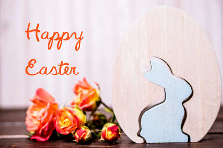 Happy Easter. close-up of wooden easter egg and easter rabbit with rose flowers on wooden background. template with copy space. easter greeting card.の写真素材