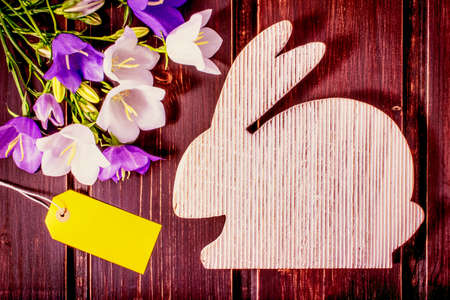Happy Easter mockup. wooden rabbit with spring flowers and sale label or tag with copy space. easter mockup template. easter sale, greeting and celebration card concept. Postcard, cover and borderの写真素材