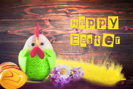 Happy Easter. Colorful easter chick, eggs and yellow feather on wooden background. greeting cardの写真素材