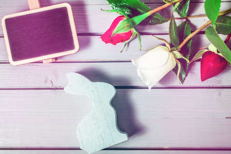 easter rabbit with rose flowers close-up, gift box and sale chalkboard on wooden background. easter mock-up template. easter sale, greeting and celebration card concept.の写真素材