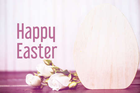 Happy easter. close-up of wooden easter egg and rose flowers on wooden background. template with...