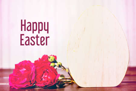 close-up of wooden easter egg and rose flowers on wooden background. template with copy space. easter concept and easter greeting card.の写真素材
