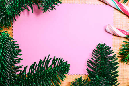Christmas candy cane and fir tree branch on wooden background. Xmas presents concept with copy space. Christmas border or greeting cardの写真素材