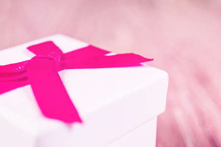 White gift box with red ribbon on wooden background. Birthday and greeting cardの写真素材