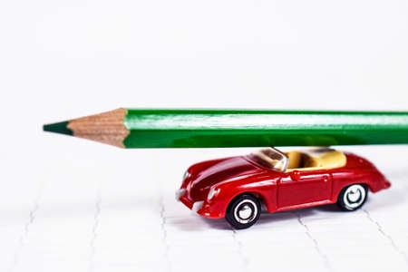 Green pencil on red toy car on wooden background. Art and back to school card.の写真素材