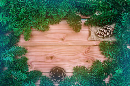 Happy Christmas. Christmas pine cone on wooden background. Xmas frame with fir tree branches. Xmas...