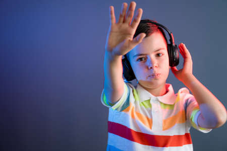 Cute boy with headphones on color liht backgroundの写真素材
