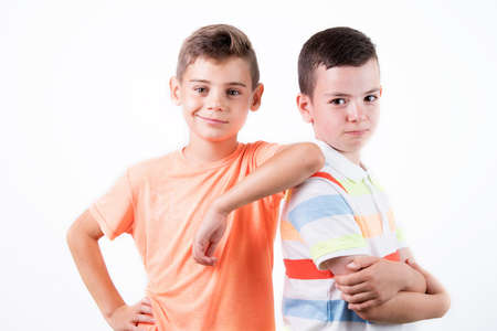Two happy young boys stand together against the white backgroundの写真素材