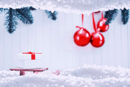 Happy Christmas. Christmas gift box on sledge in snow. red christmas balls with fir tree branches and snow frame. Xmas greeting card and border with copy spaceの写真素材