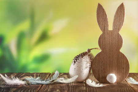 Easter Bunny with easter egg on spring background with leaves grass with sunshine. Easter greeting...