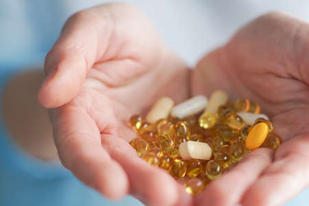 vitamins and supplements. closeup of female hands holding variety of colorful pills. close-up of womans hand taking medication tablets and capsules. Medicine Concept.の写真素材