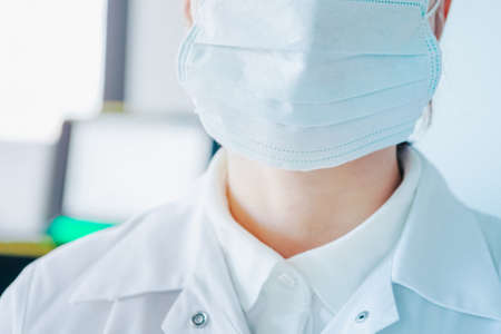 young woman in medical face protection mask indoors on laboratory backgroundの写真素材